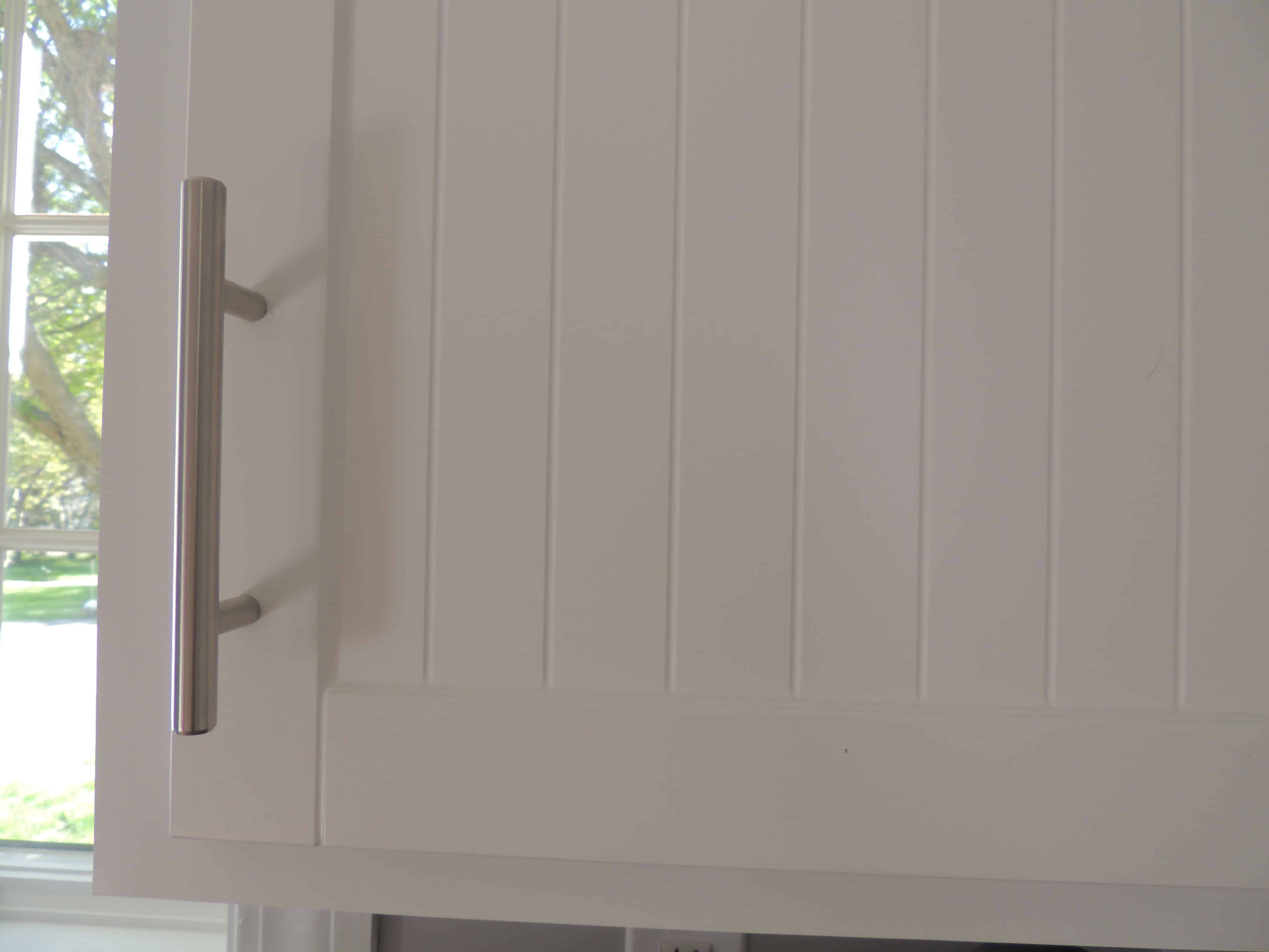 A close-up of the new cabinet doors with vertical wood paneling and silver hardware