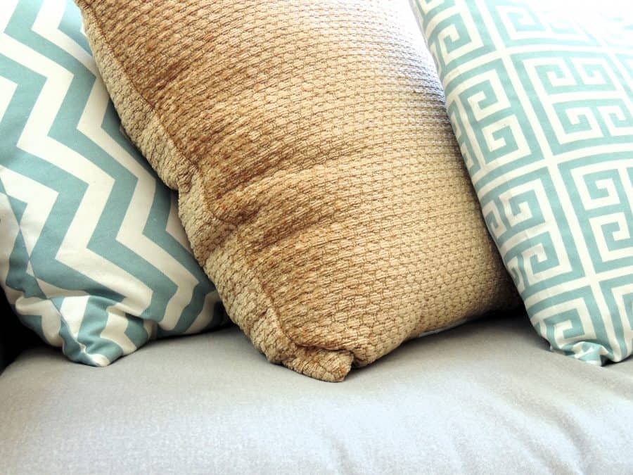 A close-up of the various patterns of the three decorative pillows in brown, blue and white