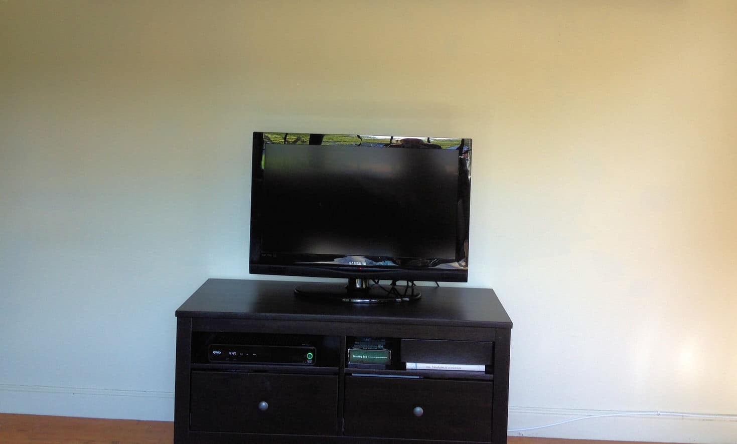 A flat screen television sitting on top of a dark, wooden table in front of a plain wall