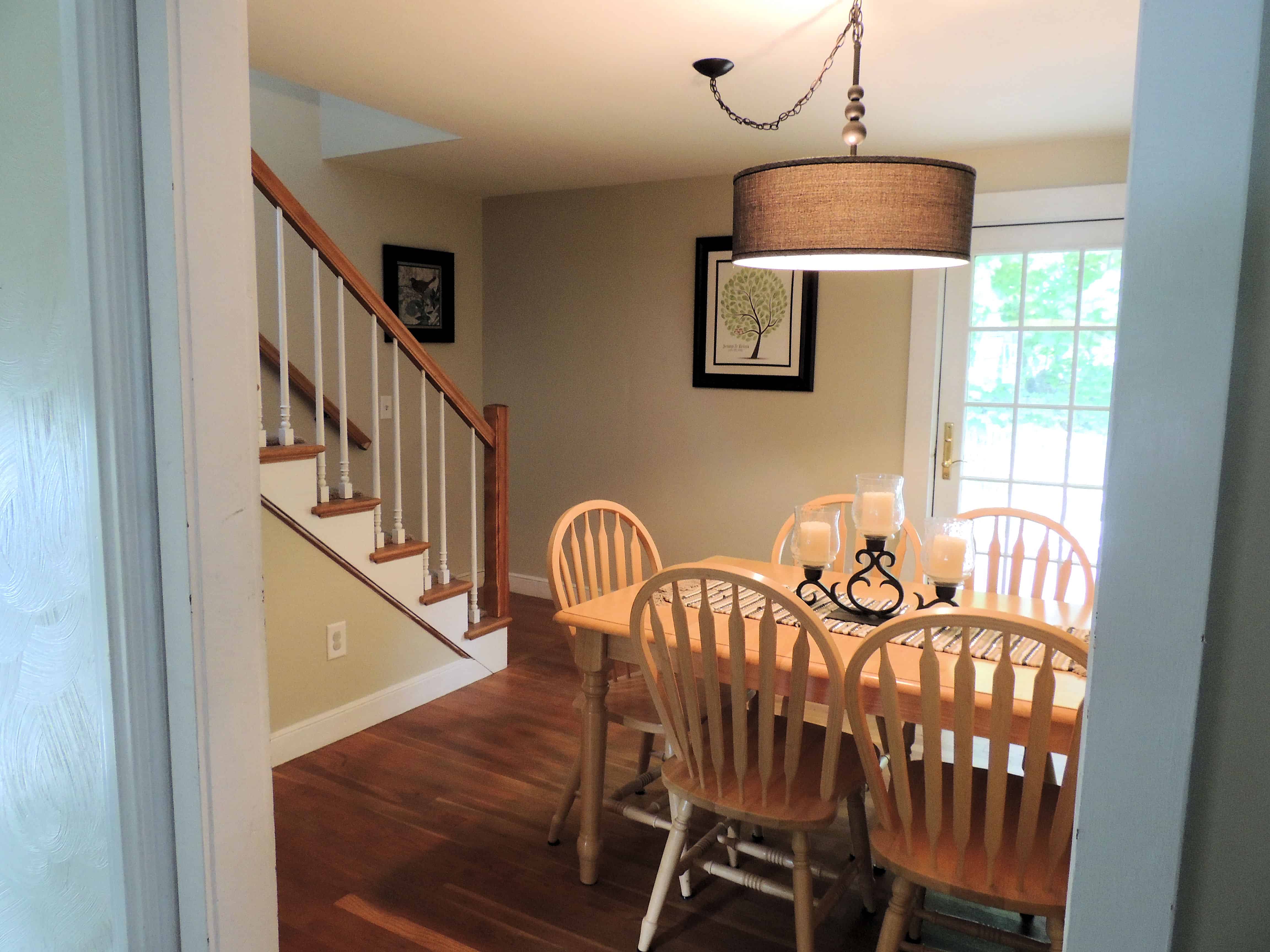 A dining room table with wooden chairs, in front of a french door leading outside