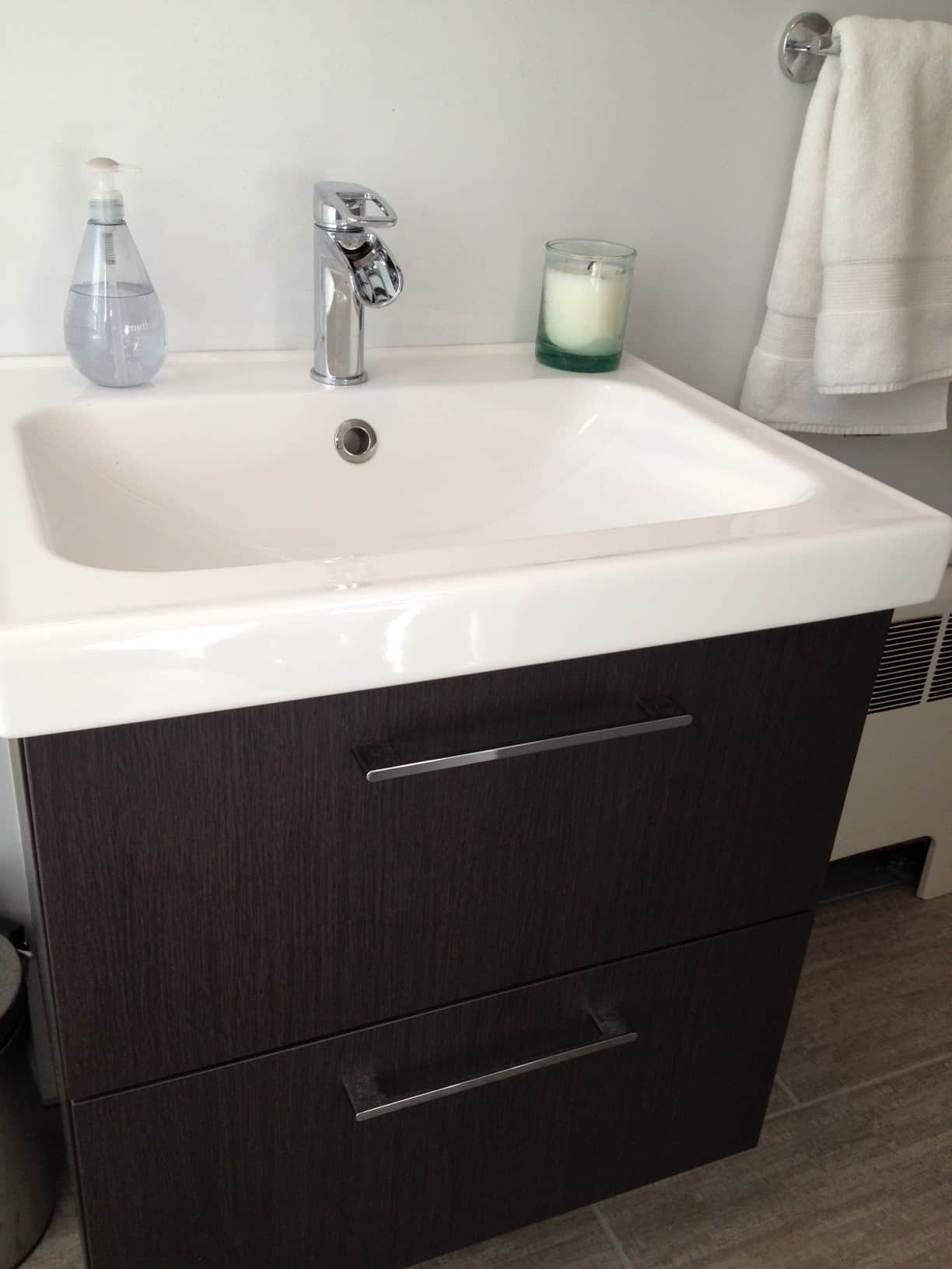 A new bathroom sink with a dark cabinet and silver faucet