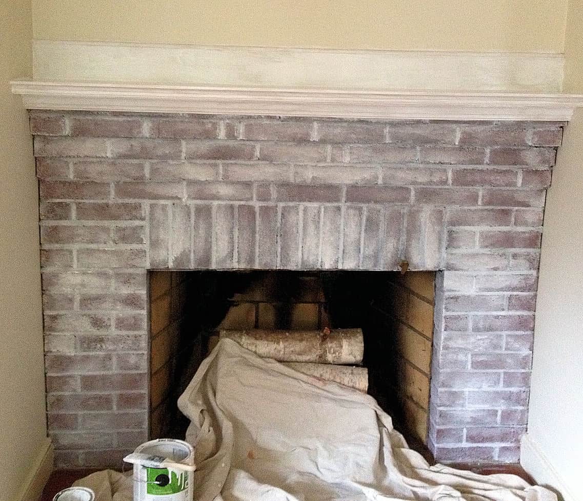 in process shot of red brick fireplace being painted with white wash