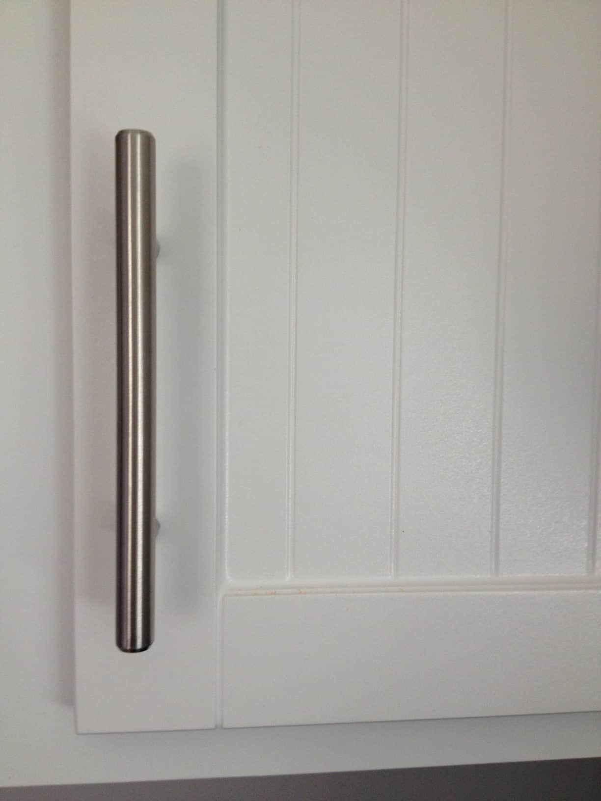 A closeup of an upgraded, white kitchen cabinet with silver hardware