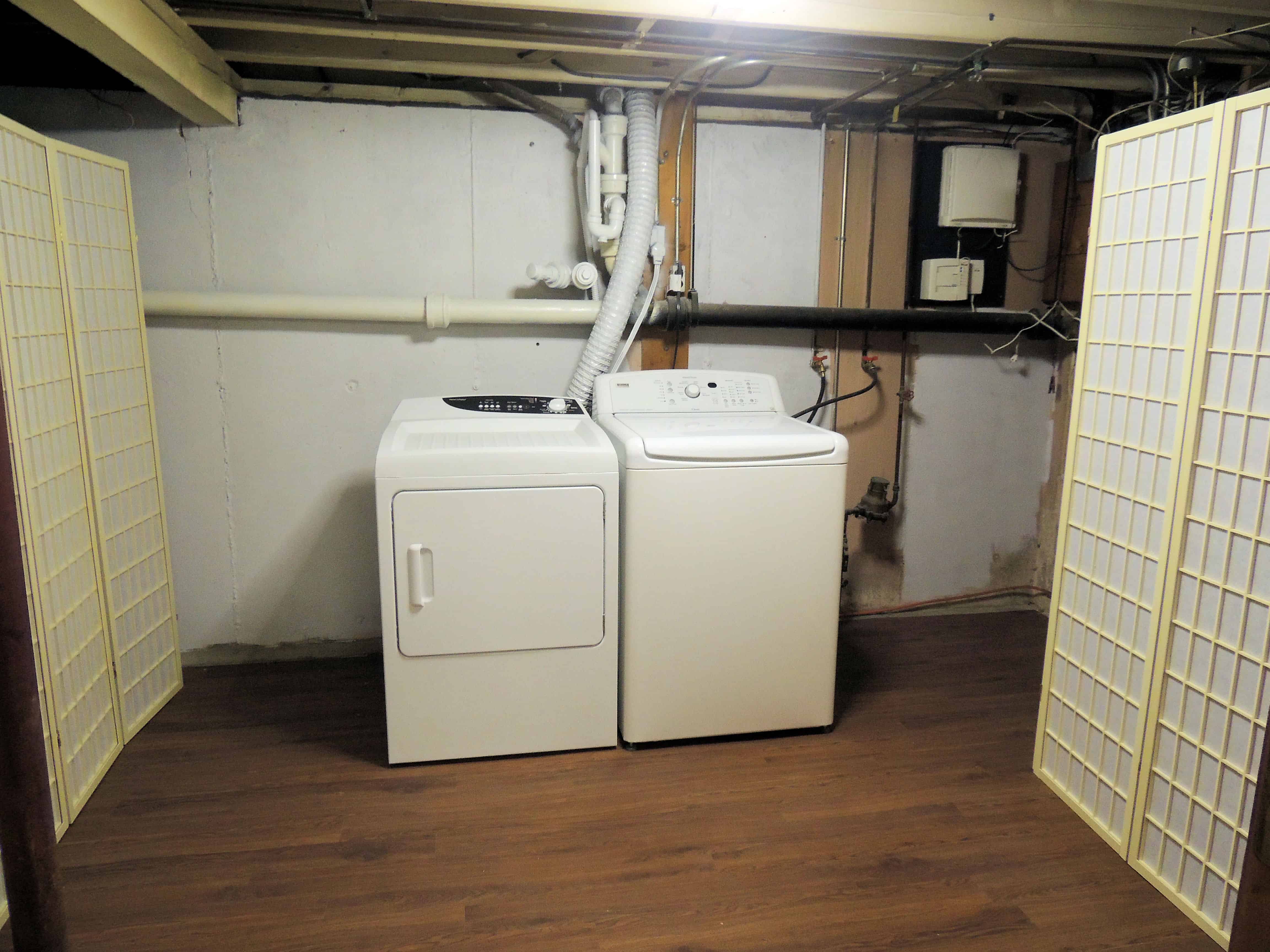 A laundry area with wood floors, and a white washer and dryer