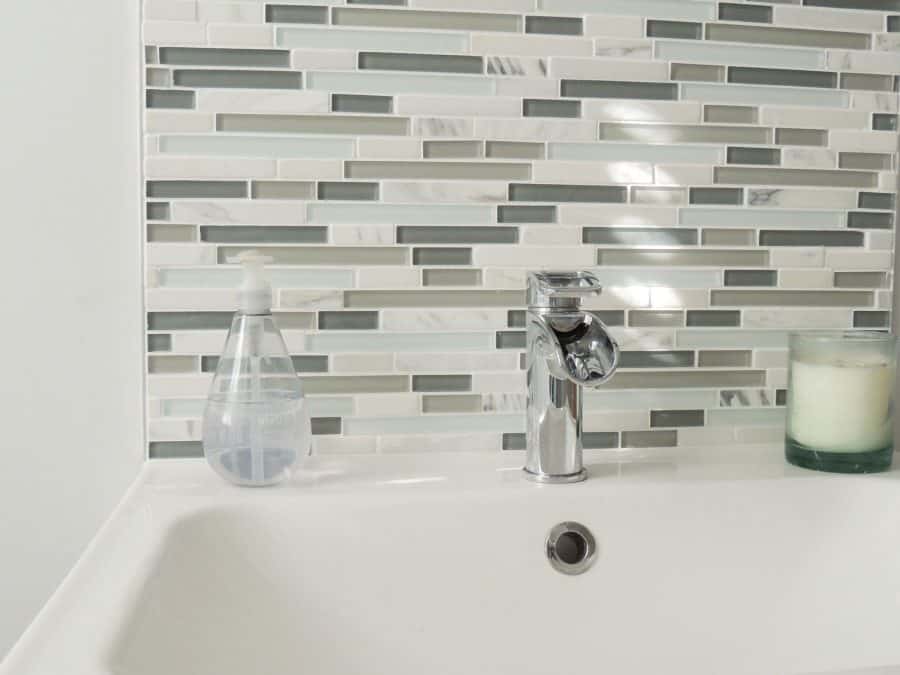 Strips of horizontal grey, white and beige tiles above a bathroom sink