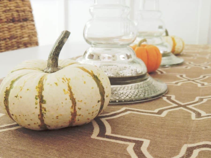 A close-up of the brown runner, with the base of the glass candle holders and a few pumpkins