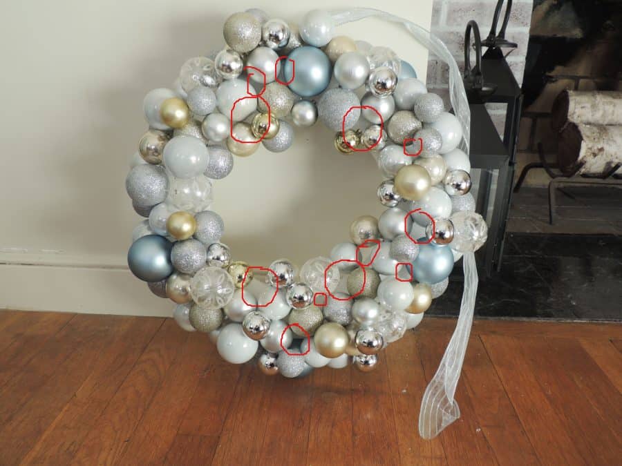 The whole wreath with all ornaments attached but highlighted with red circles where there is a gap showing the plain foam wreath form below.