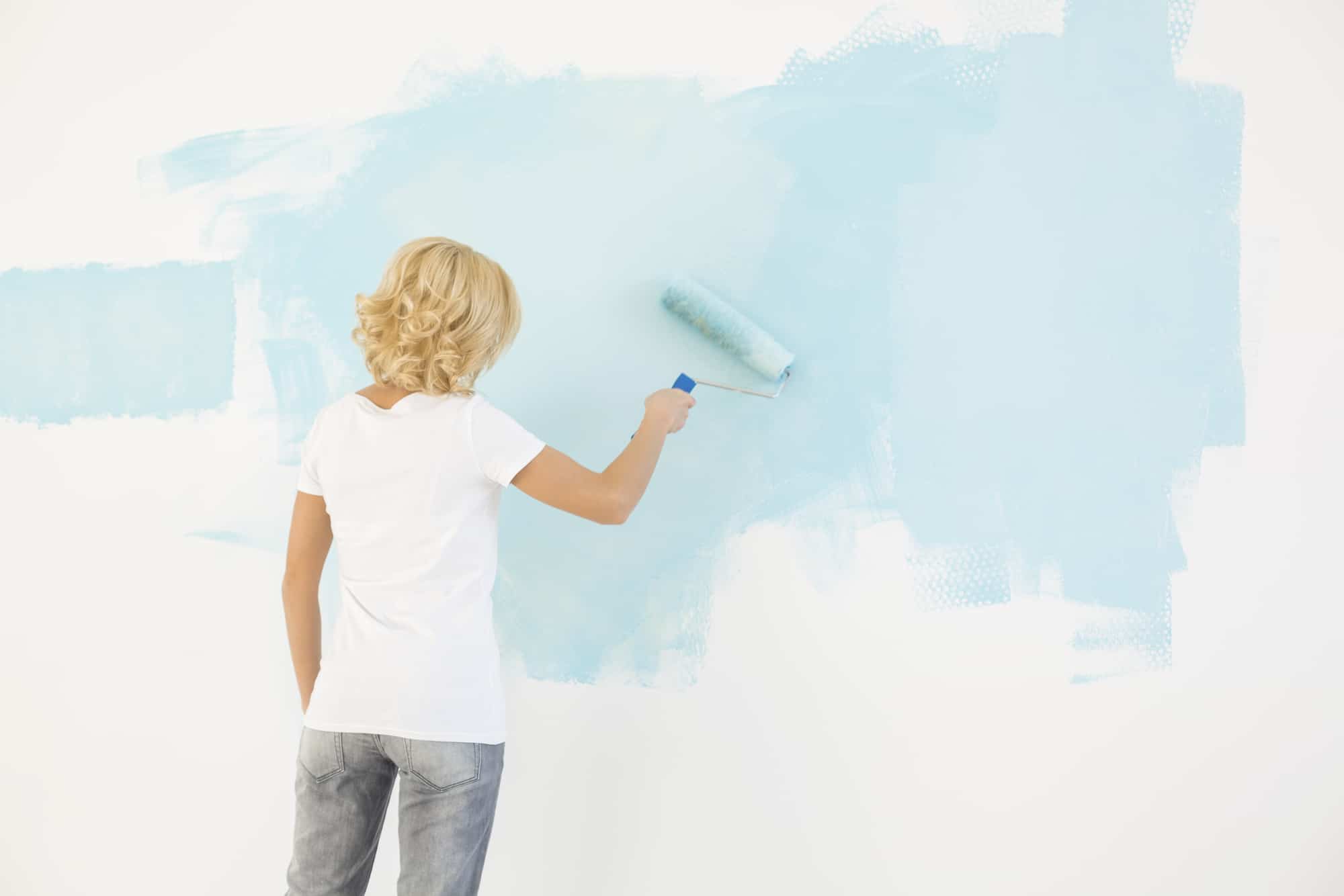 woman painting wall with a roller