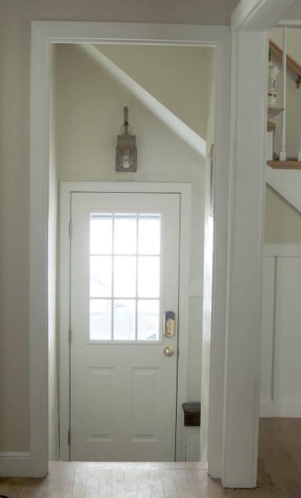 A hallway, leading towards a recessed area, with an outside door with glass panes on the top half