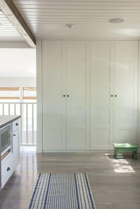 A closet with tall, white paneled doors, with a green step stool nearby