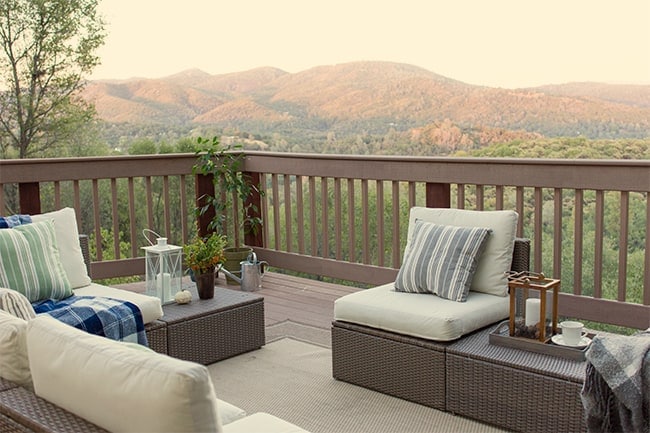 The corner of the deck, with the mountains in the background and grey wicker seating in the foreground
