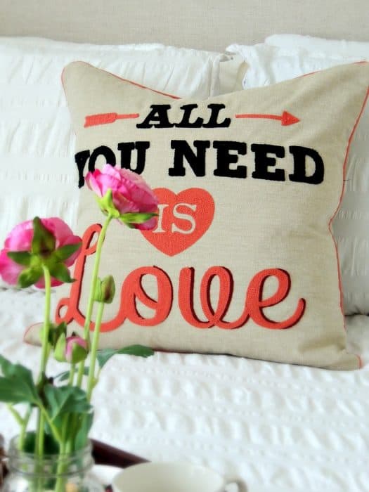 A tan-colored accent pillow with the words \"All You Need is Love\" 