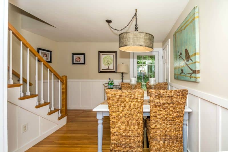 The backs of the wicker chairs, with a white table underneath a drum-shaped lighting fixture 