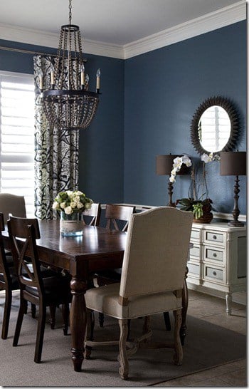 A dining room with blue walls, beige side table and dark wood elements, 