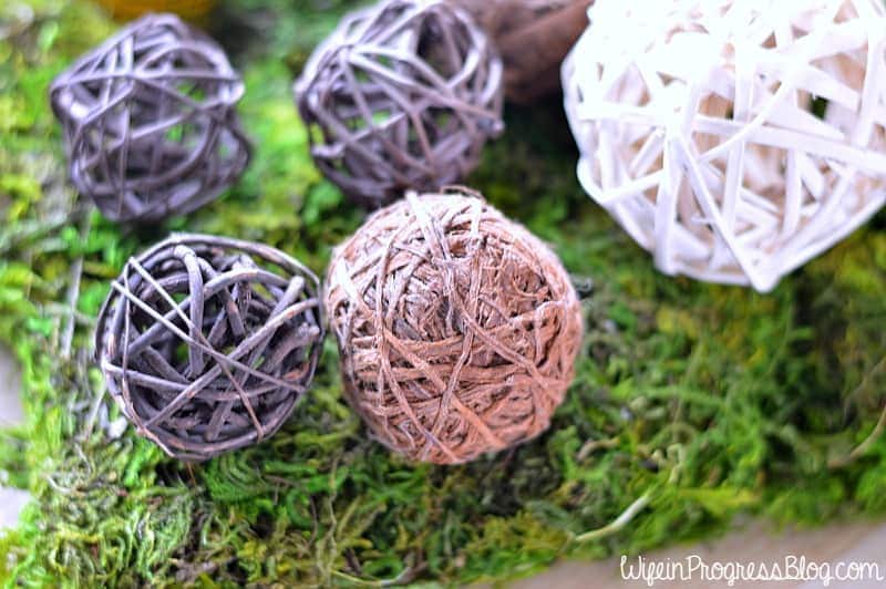 A close up of purple, pink and white rattan decorative balls resting on green moss