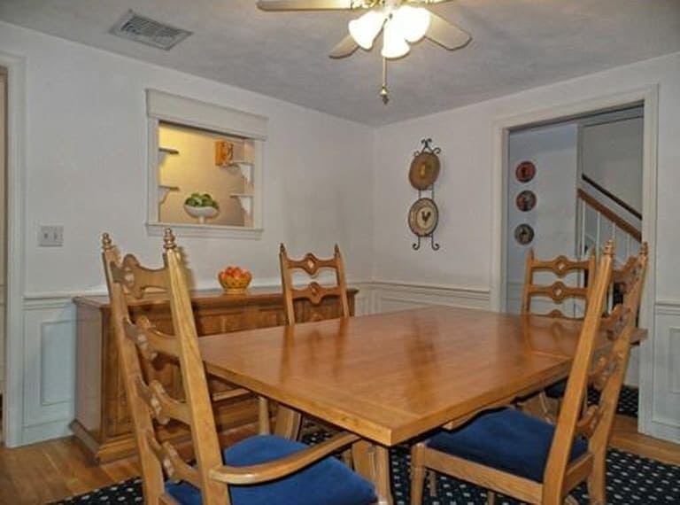 An oak dining room table with matching chairs and dark blue cushions