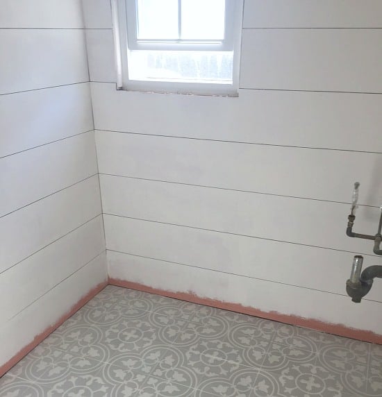 White plywood shiplap walls and gray cement tile floor