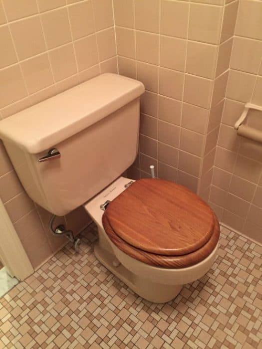 A pink toilet with wooden seat