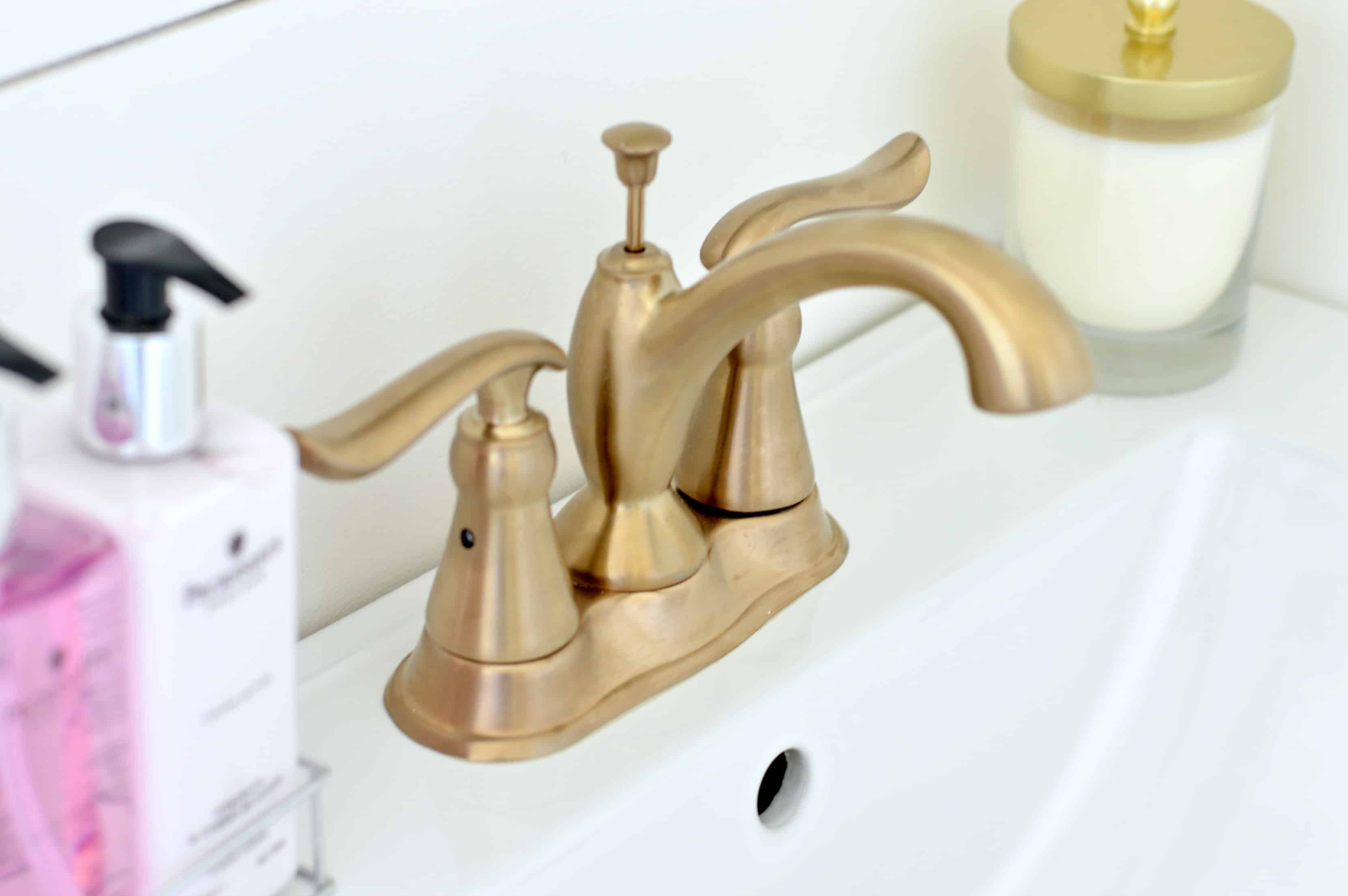 A close-up of a white sink with antique gold faucet and two handles