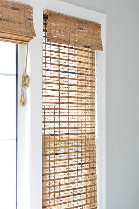 A close up of a window with a sheer, wooden blind pulled down