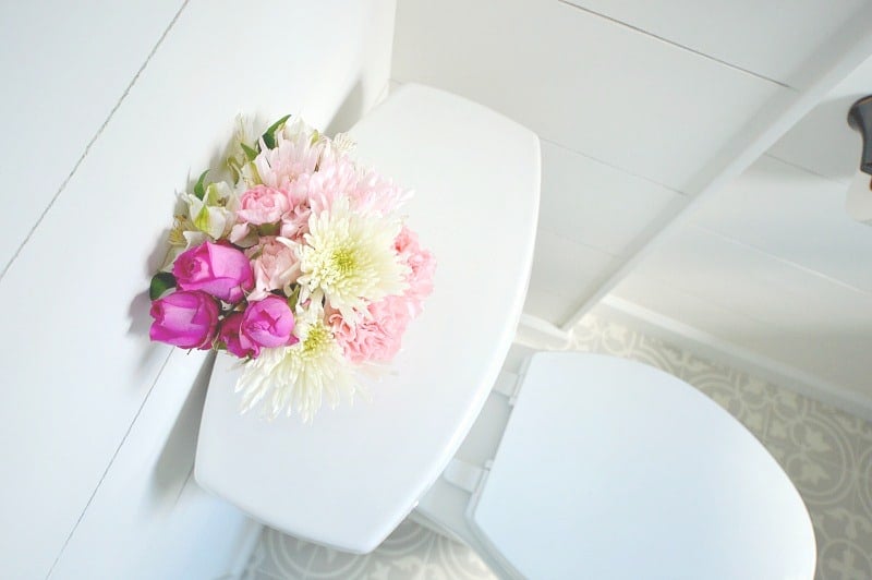 A top view of the flowers in a vase on top of a new, white toilet