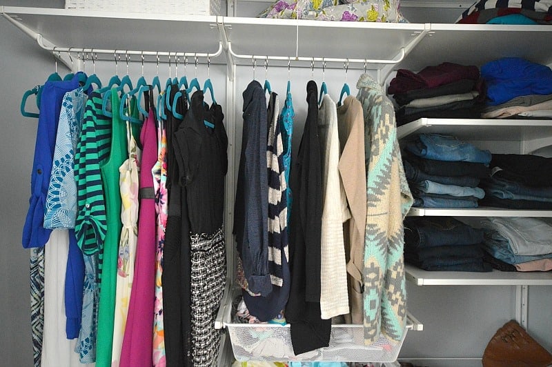 Colorful dresses, sweaters, tops and jeans hung up or stacked on the shelves of a new closet organizer system