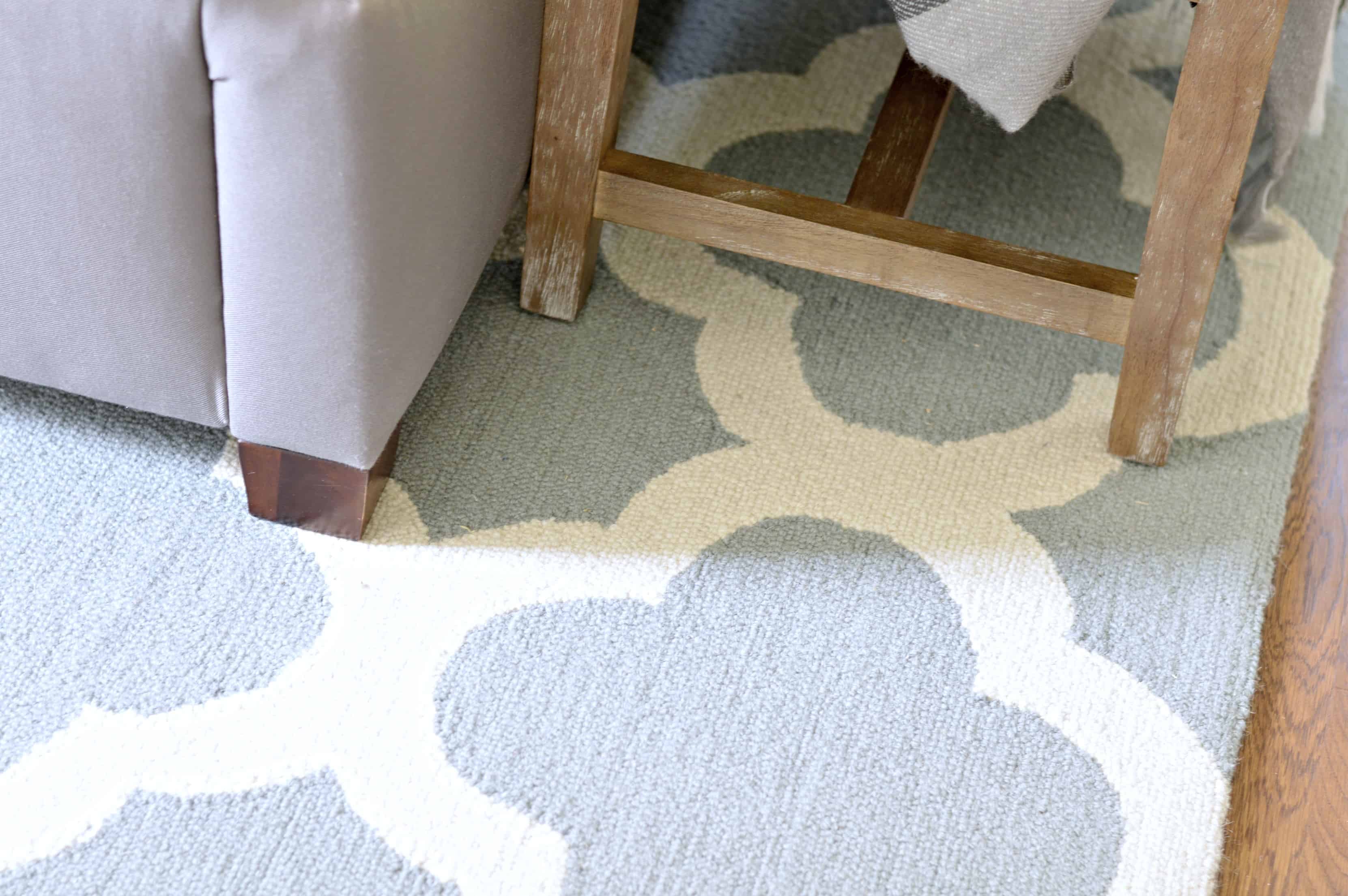 The bottom of the bed and bench, showing the details of a light blue and white area rug