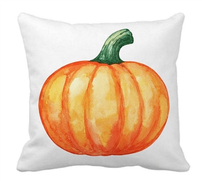 A transferred design of a large, orange pumpkin onto a square, white pillow