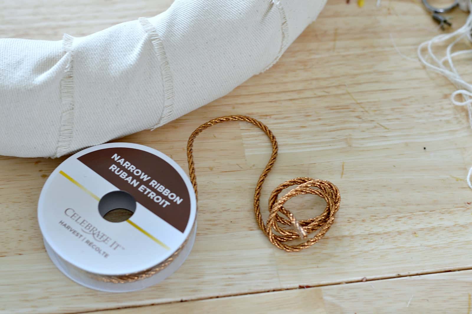 The edge of a wreath, wrapped in burlap and a roll of copper-colored twine