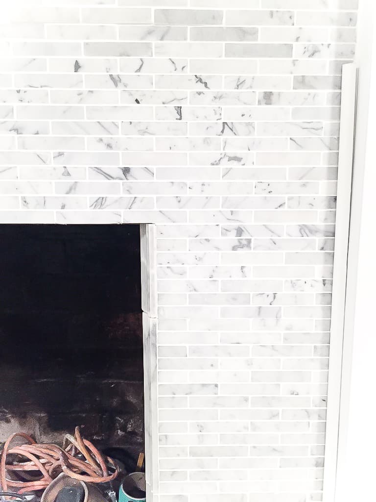 A close-up of the narrow, rectangular grey and white tiles in the fireplace surround