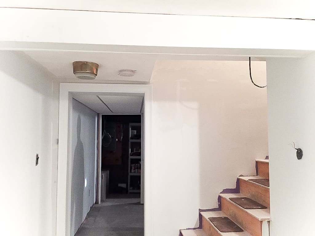 A side view of the bottom of a staircase and a door leading to other areas of a basement