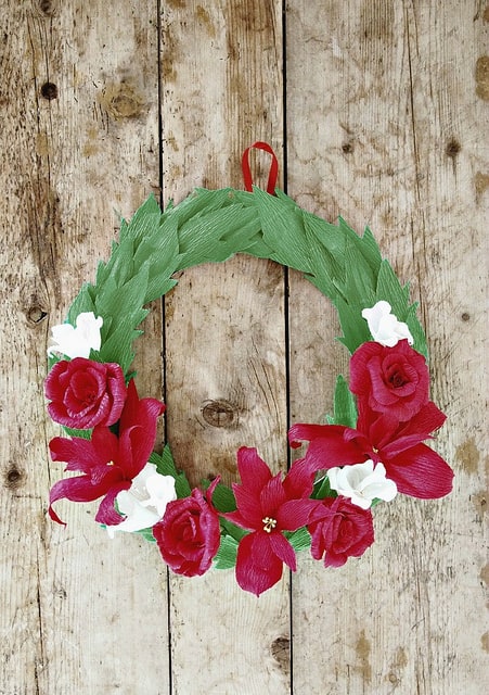 A green wreath with red and white flowers on the lower half