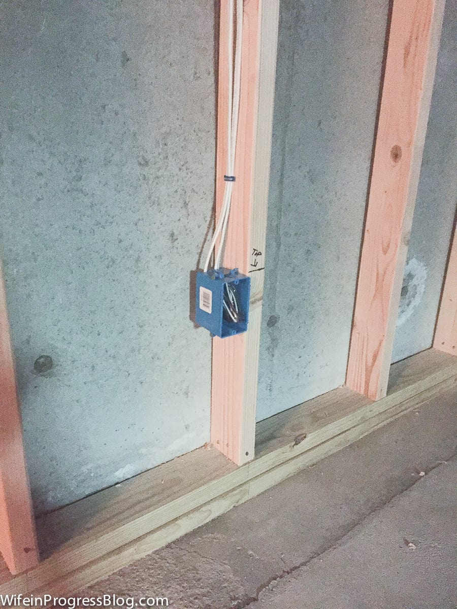 A close-up of the electrical work, wooden frame and drywall installed to build a dividing wall in the basement
