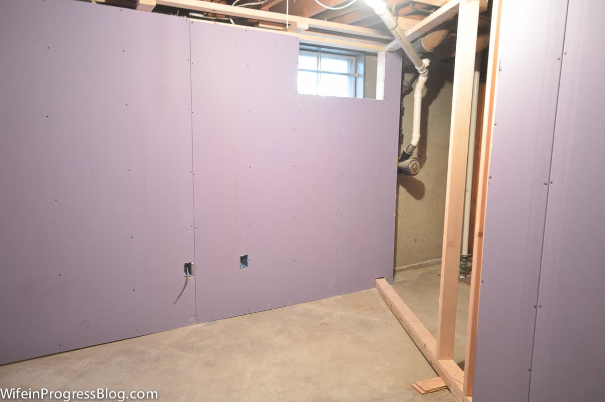 Sheets of drywall installed to wooden frames, with a cutout for a small window on top