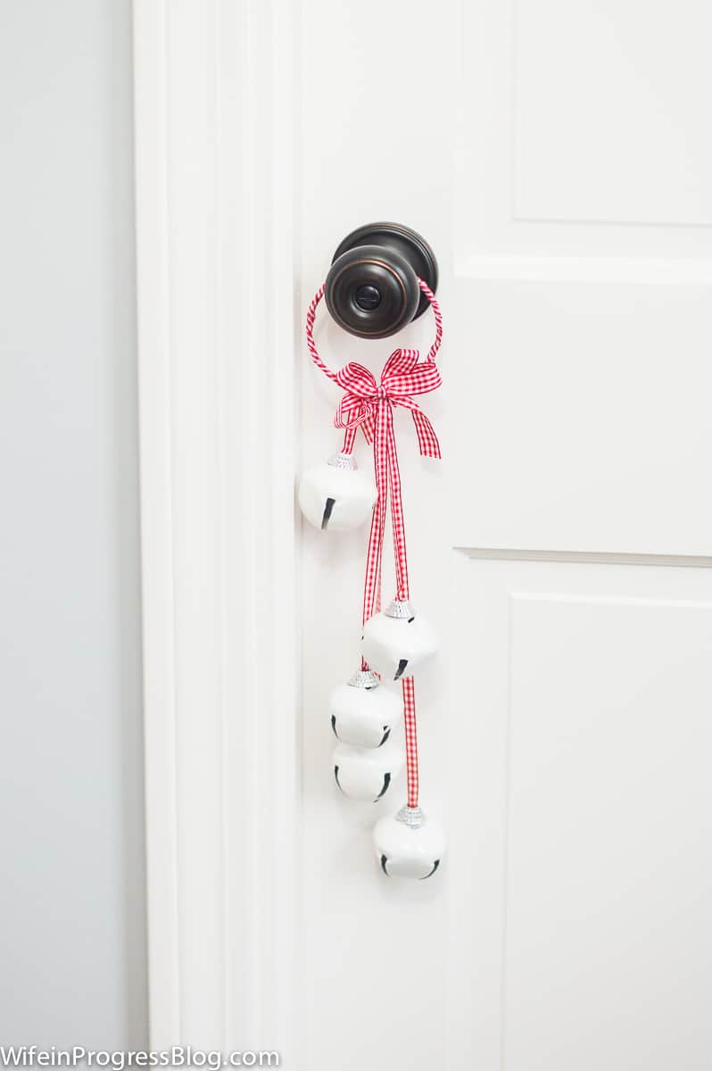 A ring with red gingham ribbon holding bells, hung from a door knob