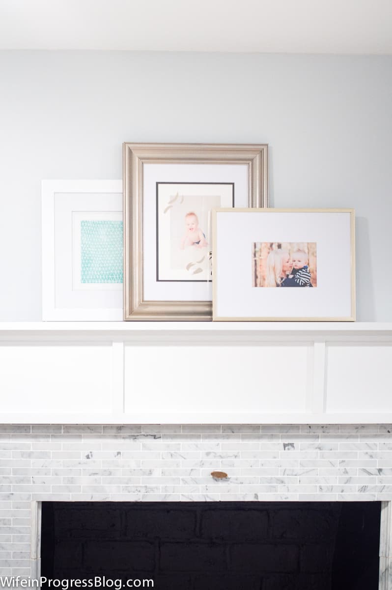 Three photo frames, resting on top of a wooden fireplace mantel