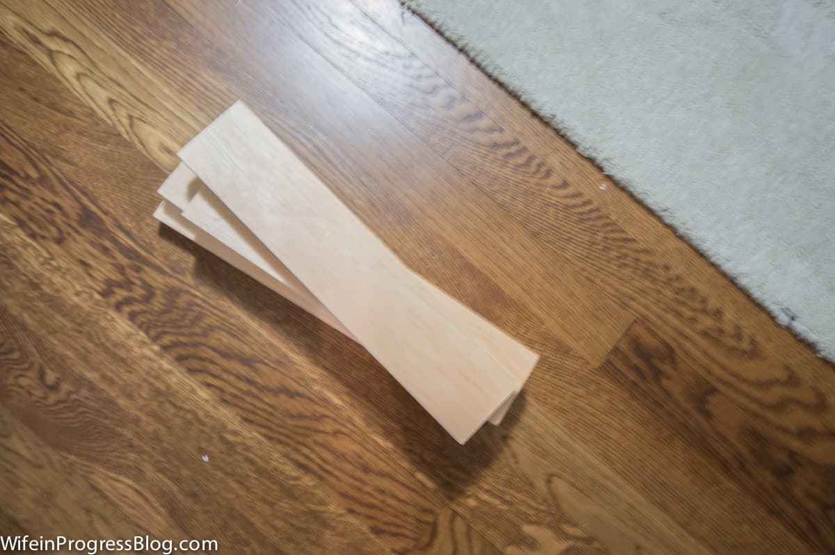 A stack of thin pieces of natural wood, on a wood floor