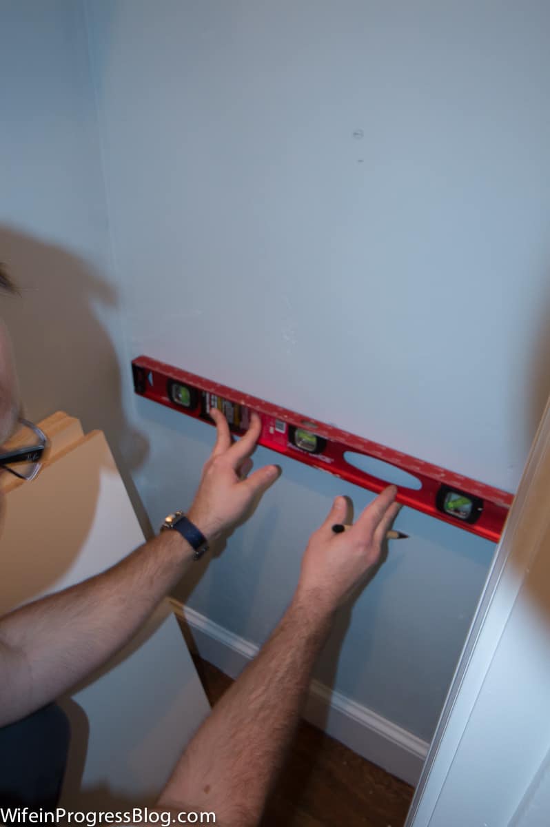 A person holding a level against a light blue wall