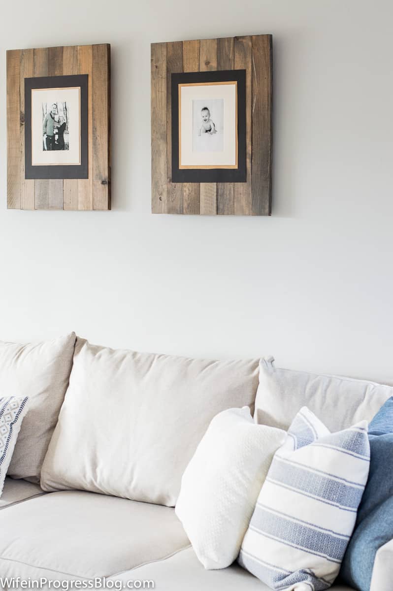 Rustic wooden frames with family portraits above the living room sofa