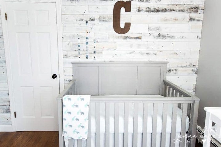 Reclaimed wood accent wall is all done - gray crib positioned in front of wall with a few wall decor items added