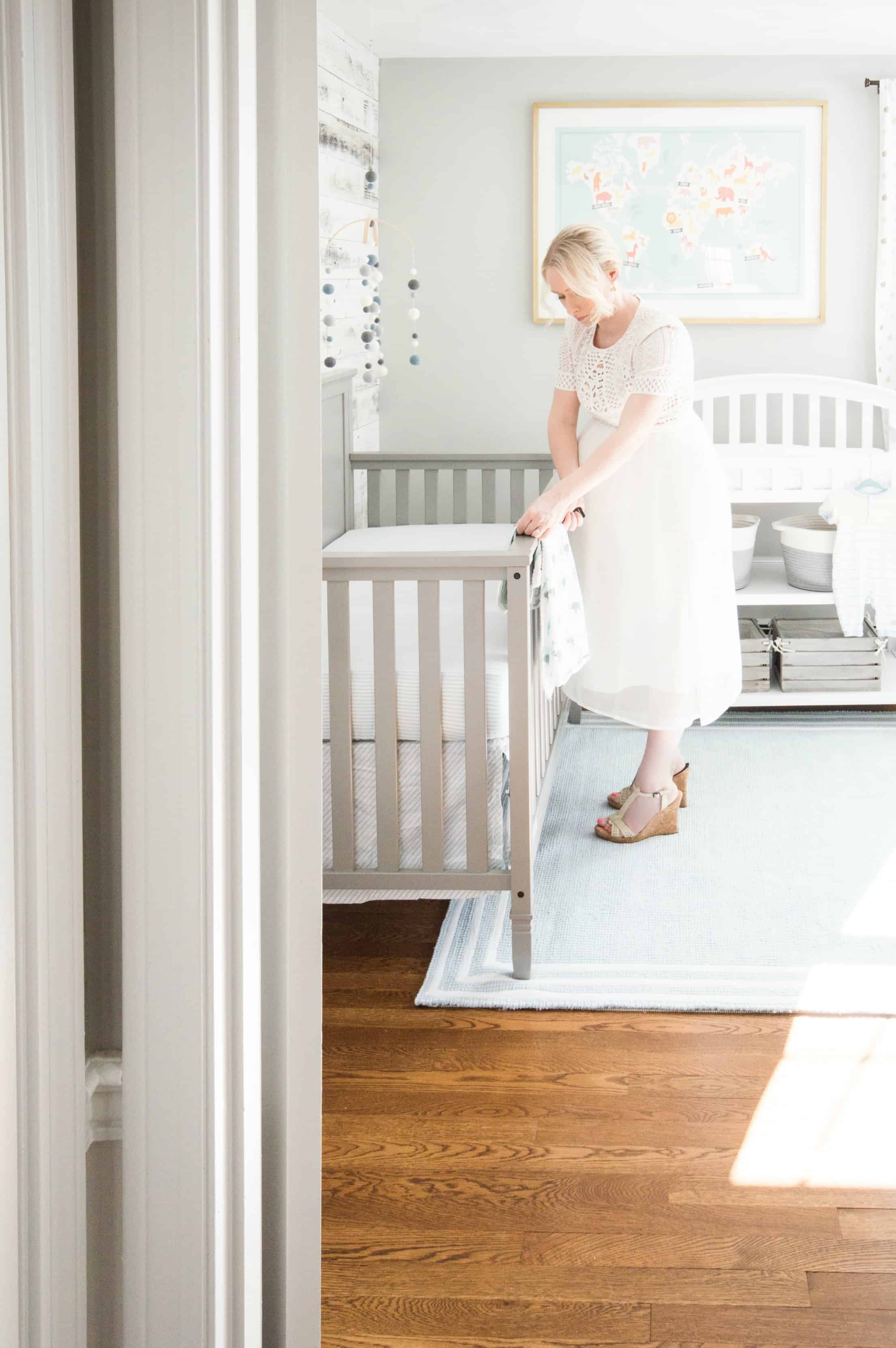 Mom setting up classic grey and blue nursery