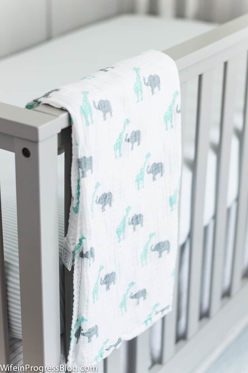 Grey crib with animal printed swaddle in baby boy nursery