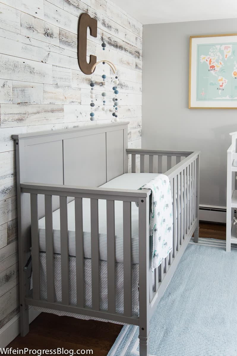 Blue and grey themed nursery with reclaimed wood accent wall and grey crib.