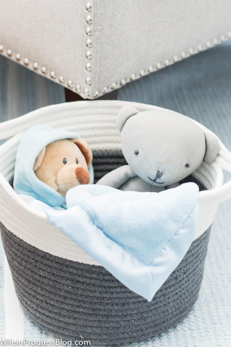 Stuffed animals and blanket nestled in grey and white bins in nursery