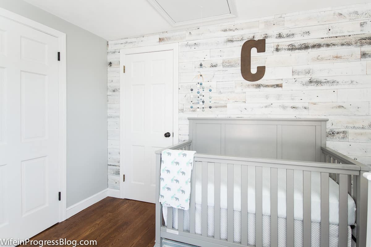 original room with gray crib and rustic planked walls
