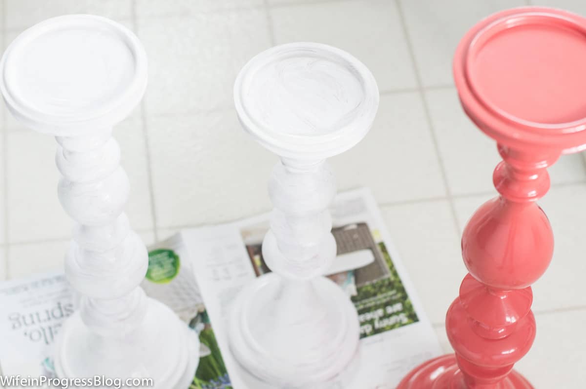 A second coat of homemade chalk paint applied to 1 candlestick, with original coral candlestick contrasted nearby