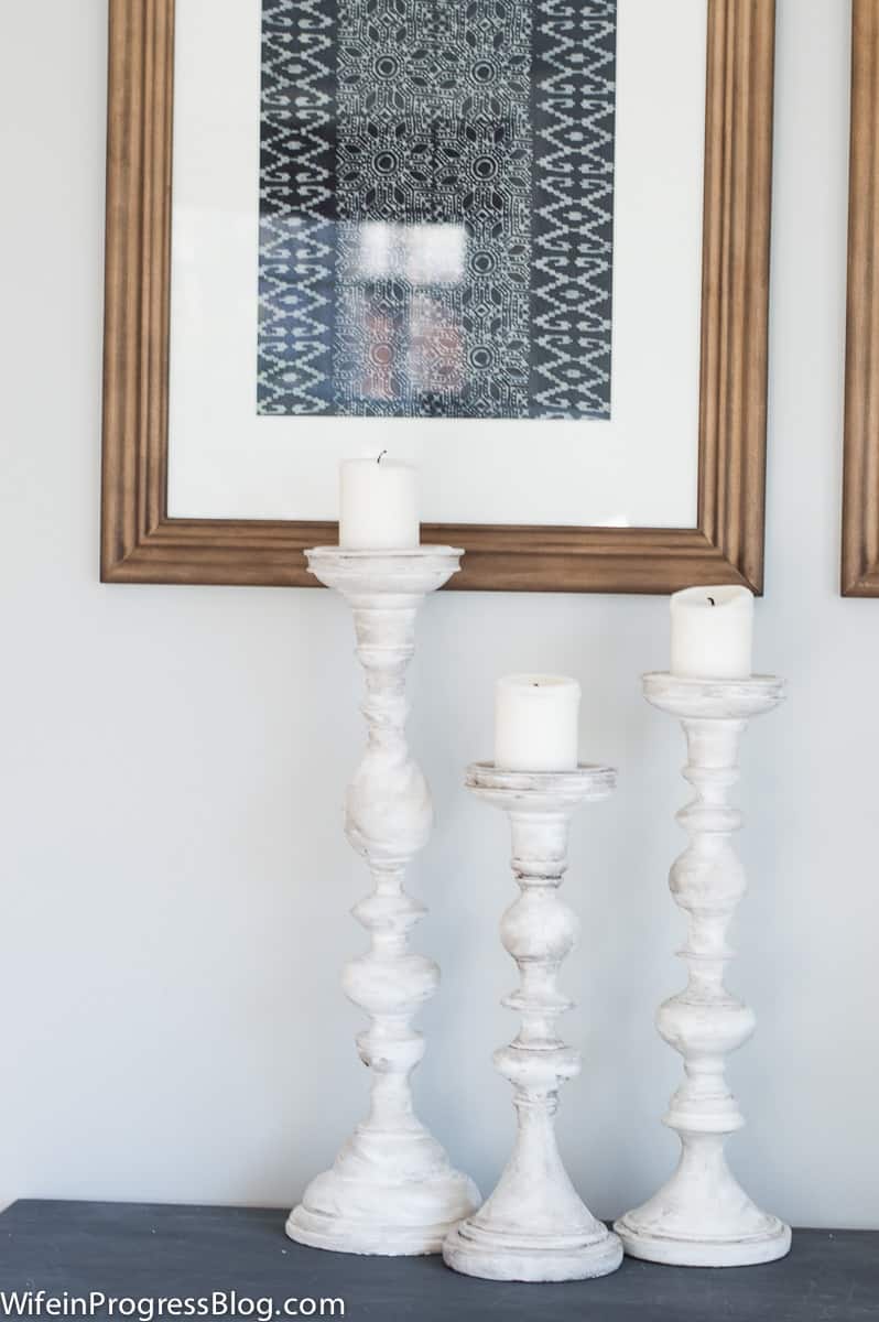 A trio of tall candlesticks on a blue table near a large photo frame