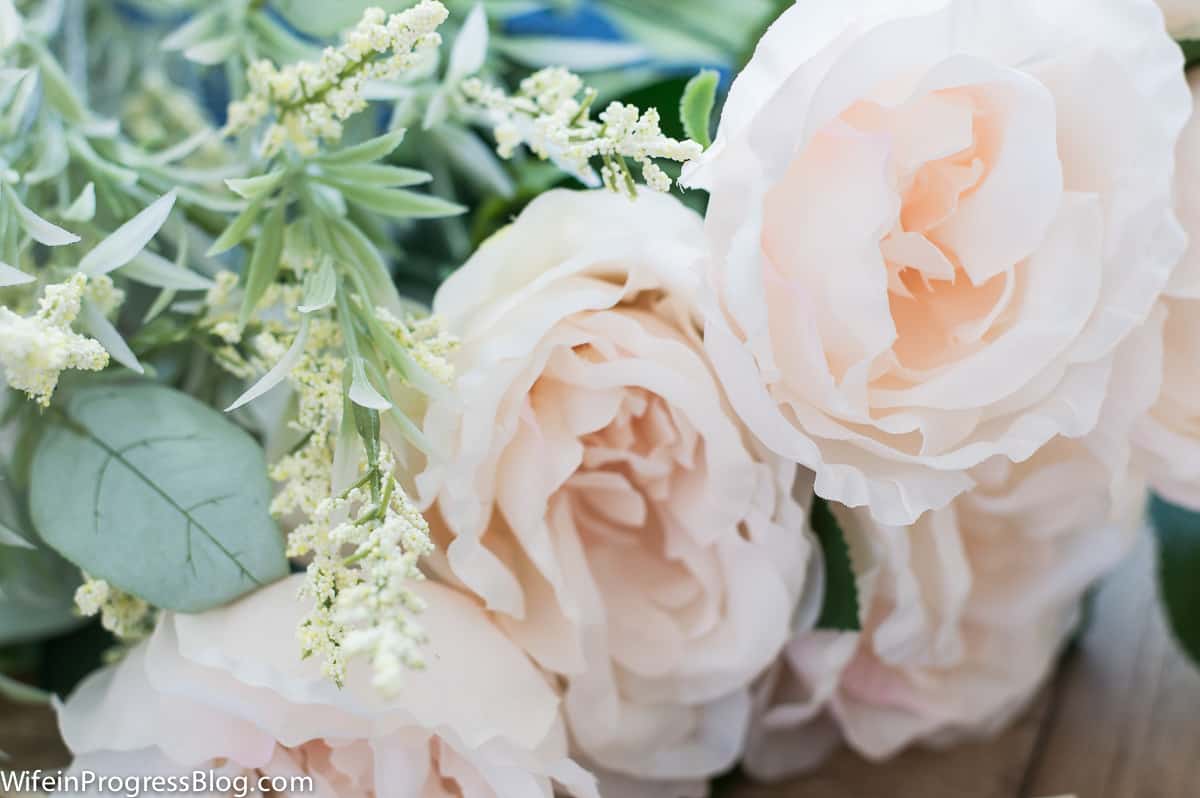 A close up of light pink flowers and greenery to be used in the spring wreath