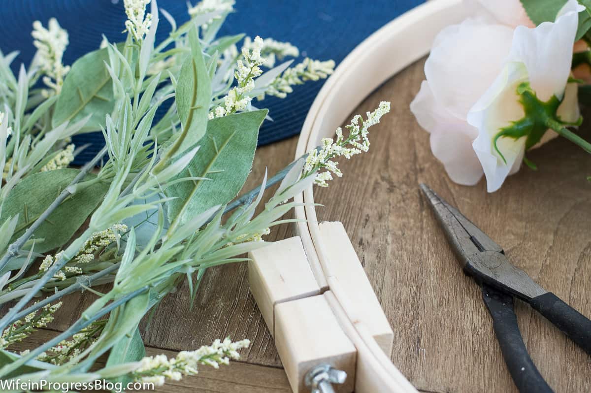 A few sprigs of greenery near the embroidery ring and a pair of pliers