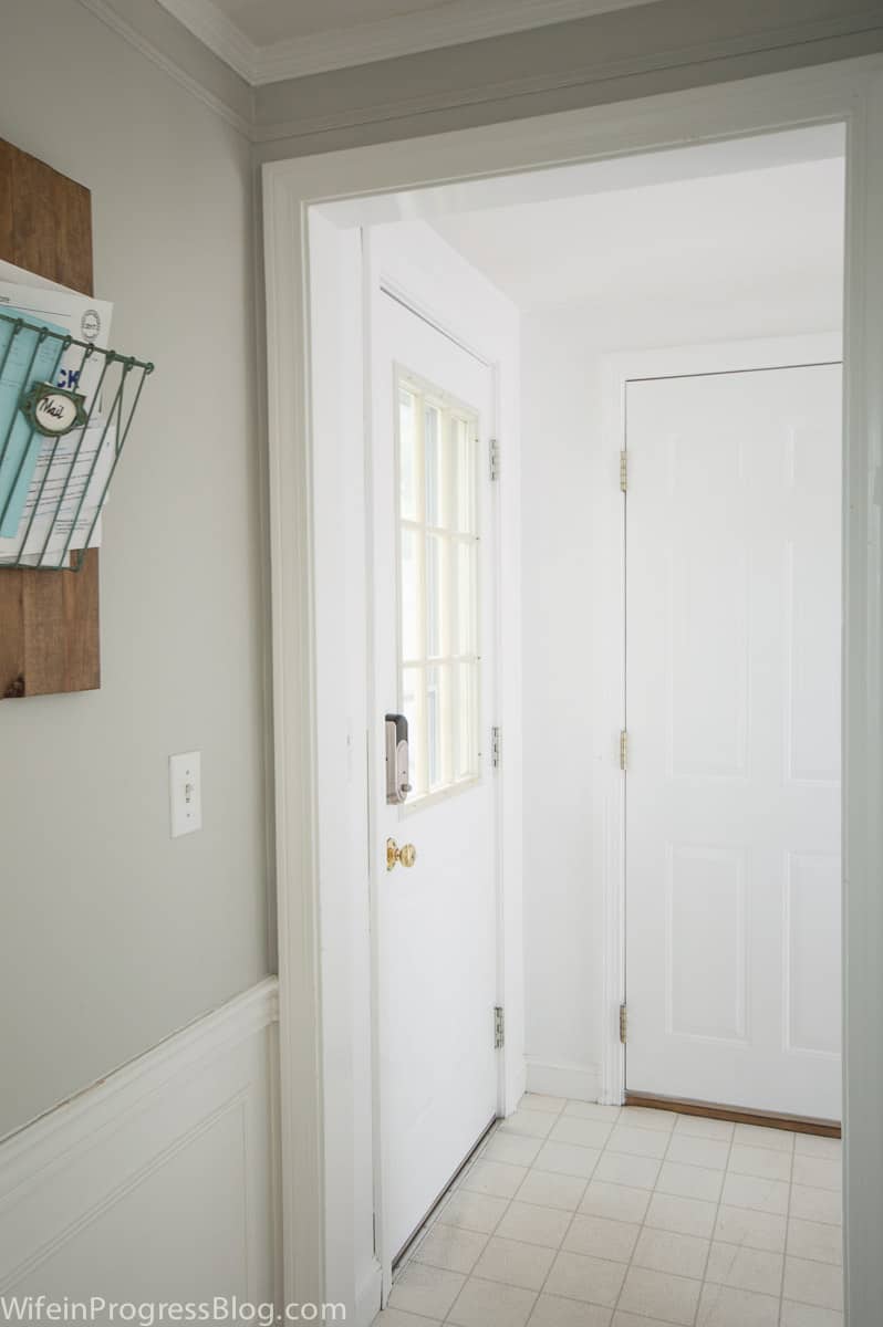 A side view of the door leading outside, with a tiled floor and a stack of mail in a hanging basket on the left